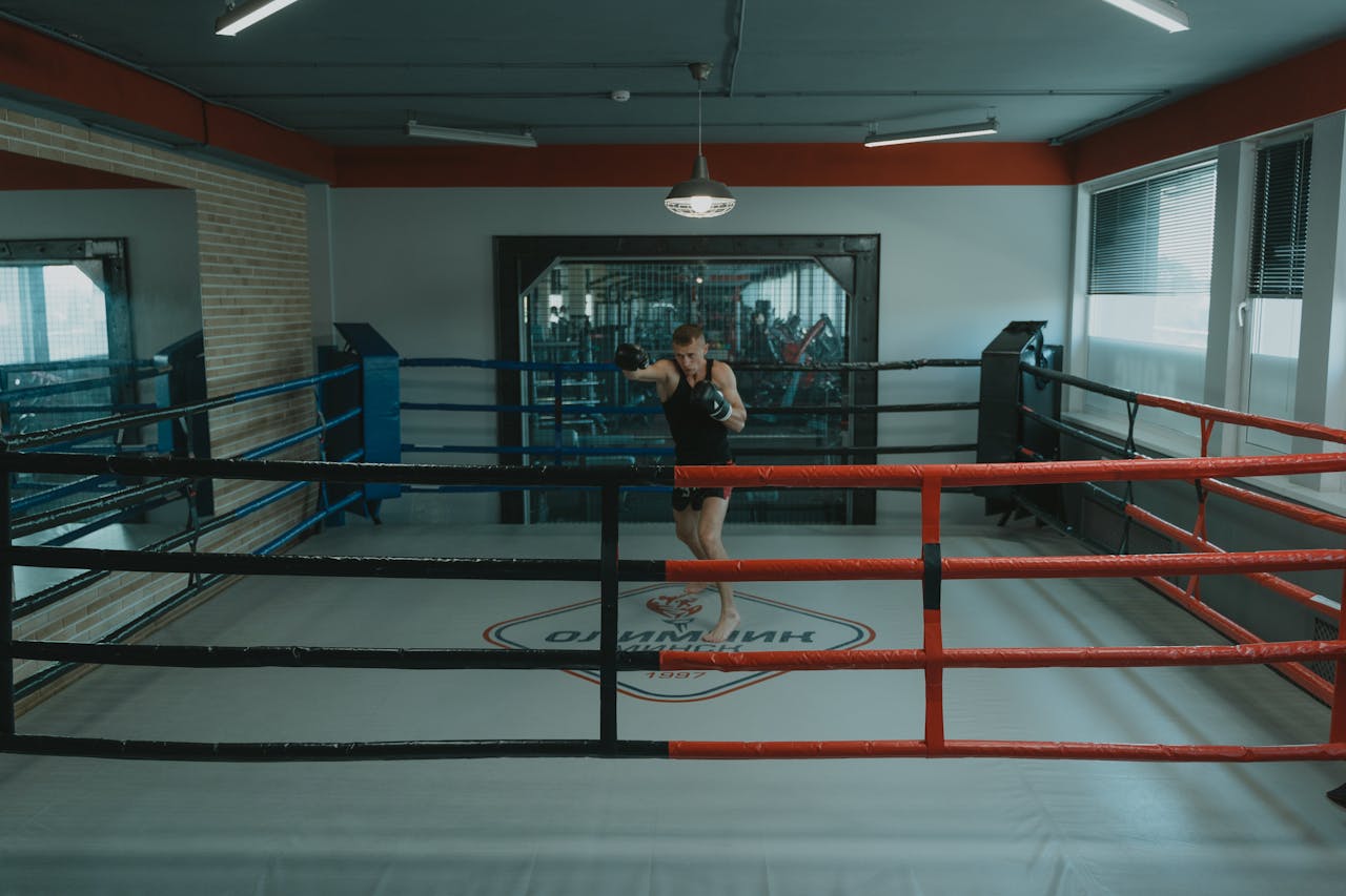 class-01 A professional boxer training alone in a well-lit boxing gym ring, showcasing focus and strength.
