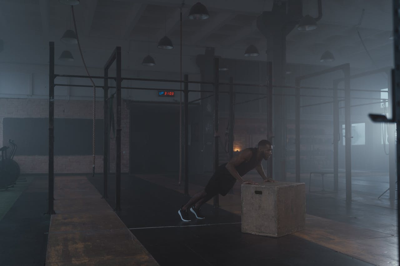 our-approach African American man focused on a box push-up workout inside a dimly lit gym.